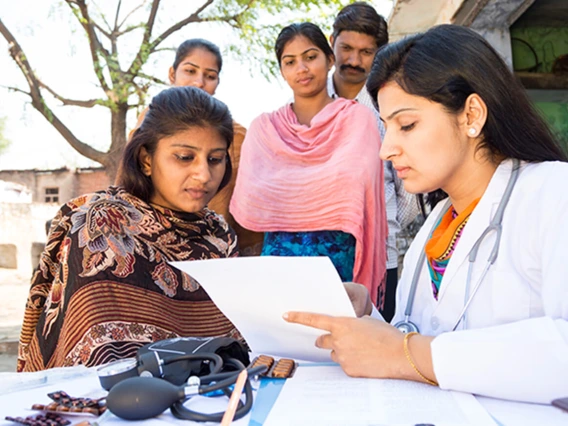 Doctor performing checkups with a female patient and her family in India